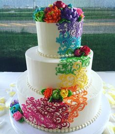 a multi - tiered wedding cake decorated with colorful flowers and pearls on a table