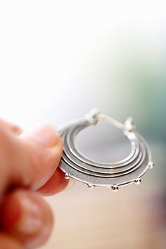 "Evocative of raindrops striking a pool of water, circles radiating outward from the point of impact and smaller droplets becoming airborne. These earrings are made completely of sterling silver, right down to the ear wires which are hinged and connect in a catch on the other side. The line and ball design is repeated on both sides of each earring. Each hoop measures approximately 1.25\" in diameter. The hoops have been given a patina to darken them and then tumbled in steel shot to give them a Unique Teardrop Hoop Earrings For Everyday, Raindrop Earrings, Earrings Silver Hoops, Ball Design, Earrings Round, Sterling Silver Hoop Earrings, Sterling Silver Hoops, Rain Drops, Earrings Sterling Silver