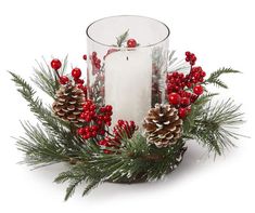 a candle and some pine cones on a white surface with red berries, holly and mist