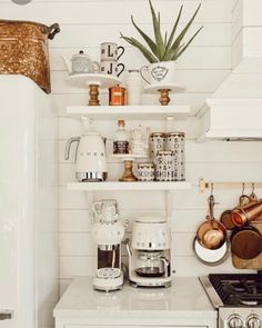 a kitchen with white walls and shelves filled with pots, pans and utensils