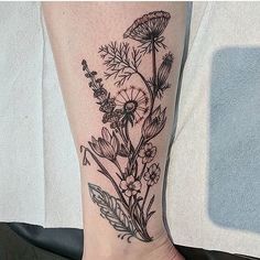 a black and white flower tattoo on the leg with an arrow in front of it