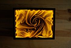 a square shaped object with yellow and black swirls on it's surface in a wood paneled room