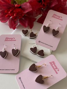 three pairs of heart shaped earrings sitting on top of a card next to a red flower