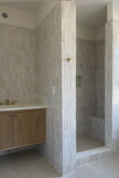 a bathroom with two sinks and a shower stall in it's corner, surrounded by white tiles