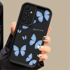 a woman's hand holding a phone case with blue butterflies on it and black background