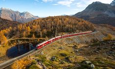 a red train traveling through the mountains