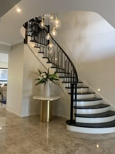 a spiral staircase in a modern home with marble floors and white walls, surrounded by glass vases