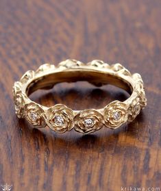 a gold wedding band with three diamonds on the top and bottom, sitting on a wooden surface