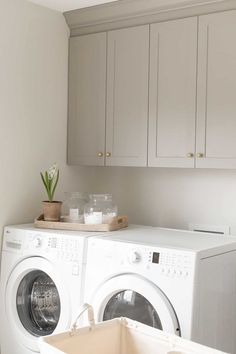 a white washer and dryer in a room with wooden cabinets on the wall