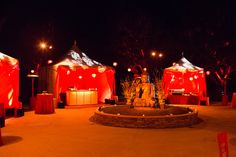 an outdoor event with red and white tents, lit up by lights on the ground