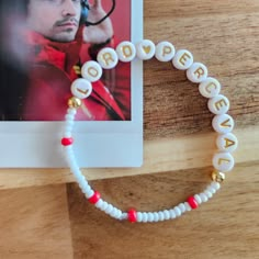 a white beaded bracelet with the word love spelled in gold letters and red beads