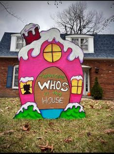 a pink house shaped sign in front of a red brick house with the words, there's some whos in that house on it