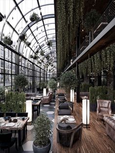 an indoor restaurant with lots of plants hanging from the ceiling and tables in front of it