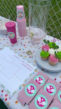 a table topped with cupcakes and pink napkins