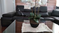 a living room with a black couch and white flowers