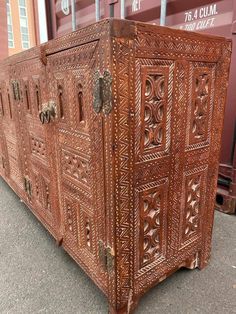 an old wooden trunk sitting in front of a shipping container on the side of the road