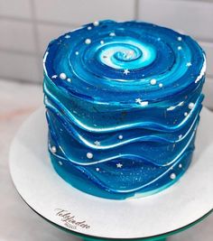 there is a blue cake with white stars on the frosting and icing in the shape of waves