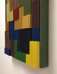 a multicolored piece of art hanging on the wall