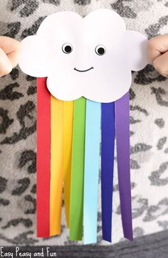 a person holding up a paper cloud with rainbows on it