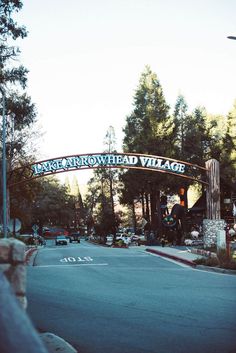 a street with a sign that says west arrowhead village on the side and cars driving under it