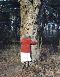 an old woman hugging a tree in the woods