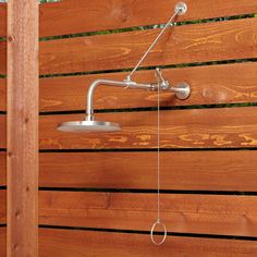 an outdoor shower head mounted on a wooden fence