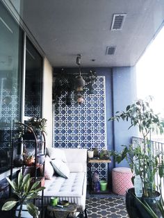 an outdoor patio with potted plants on the side and a tiled wall behind it