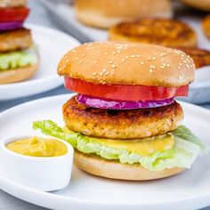 two burgers with lettuce, tomato and onion on them sitting on plates