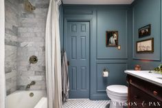 a bathroom with blue walls and marble flooring, along with a white toilet next to a bathtub