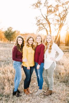 four girls standing together in a field at sunset