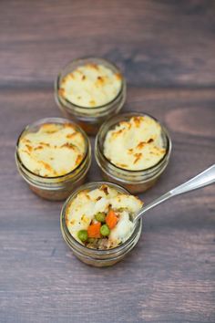 four small jars filled with food on top of a wooden table