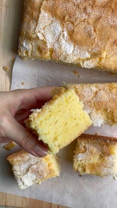 a person holding a piece of cake in their hand next to some pieces of bread