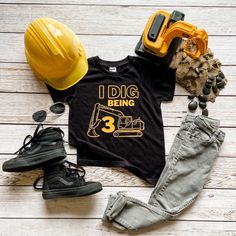 a shirt that says i dig being 3 on it next to some shoes and construction equipment