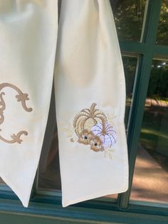 two white kitchen towels hanging on a window sill