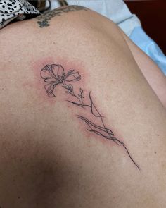 a tattoo on the back of a woman's shoulder with a flower in it