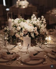 the table is set with white flowers and candles for an elegant wedding reception or special event