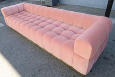 a pink couch sitting on top of a sidewalk next to a parking meter in front of a building