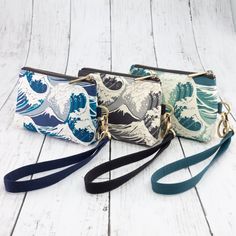 three purses with different designs on them sitting next to each other in front of a white wooden background