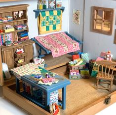 a doll house with furniture and quilts on the bed, desk, dresser and chair