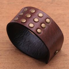 a brown leather bracelet with gold dots on it