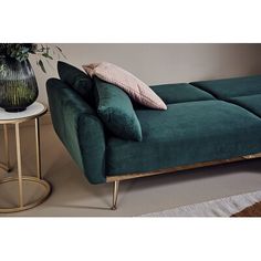 a green couch sitting next to a table with a vase on it