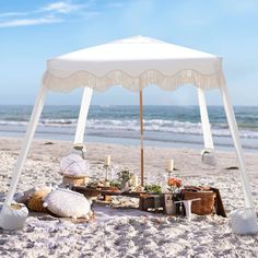 an umbrella is set up on the beach with food and drinks in front of it