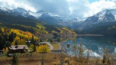 a mountain lake surrounded by trees and mountains with snow on the tops, in autumn