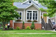 a small house with landscaping on the front lawn and stairs leading up to it's second story