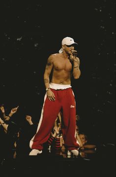 a shirtless man standing on top of a stage with his hands in his mouth