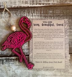 a pink flamingo ornament sitting on top of a wooden table next to a card