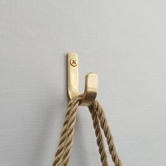 a close up of a rope on a wall with a hook in the middle and one knot at the end