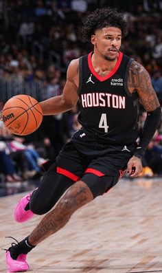 a basketball player dribbling the ball in front of an audience at a game