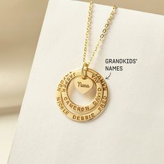 "These two rings are stamped with her loved one and a small heart charm at the center to share their love with family members. The heart charm can be engraved with however you call your grandma: nana, mimi, abuela, omi, gigi - just whichever dear to you! A perfect gift for Grandma on any occasion. ► GRANDMA NECKLACE WITH KIDS NAMES * WORD LIMIT: Small ring: 4-5 words / Big ring: 6 words. Date is counted as 2 words. *  Small ring measures approx. 3/4\" (20mm). Big ring measures approx. 1\" (26mm) Name Necklace For Anniversary Gift, Personalized Name Charm Necklaces, Personalized Open Heart Charm Necklace For Anniversary, Anniversary Jewelry With Names On Heart Pendant, Anniversary Jewelry Heart Pendant With Names, Hand Stamped Double Heart Jewelry For Anniversary, Heart Pendant Jewelry With Names For Anniversary, Engraved Open Heart Charm Necklace For Anniversary, Anniversary Hand Stamped Double Heart Necklace