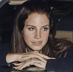 a woman sitting in the back seat of a car with her hand on her lap